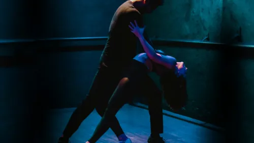Paar tanzt leidenschaftlich in schwach beleuchtetem Studio.