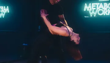 Couple dancing energetically in dim studio.