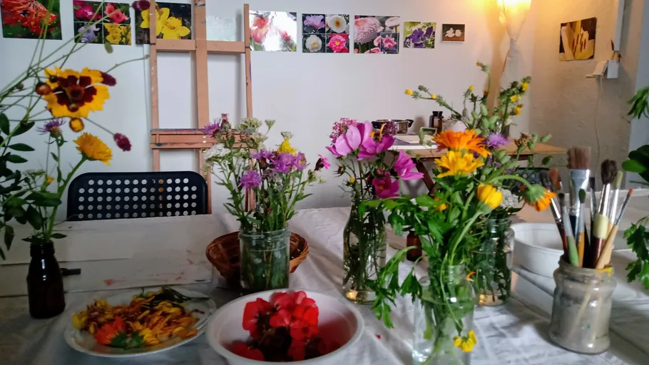 Kunststudio-Tisch mit Blumen und Pinseln.