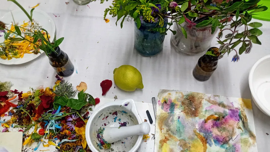 Blumen und Werkzeuge auf einem unordentlichen Tisch.