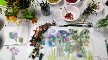 Colorful flower arrangements on a busy art table.
