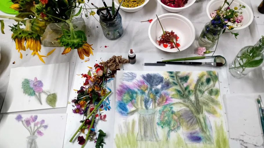 Colorful flower arrangements on a busy art table.