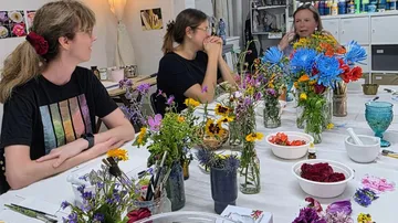 Menschen plaudern an Tisch mit Blumen.