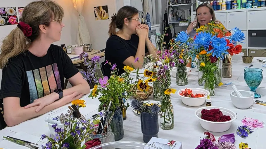 People chatting around table with flowers.