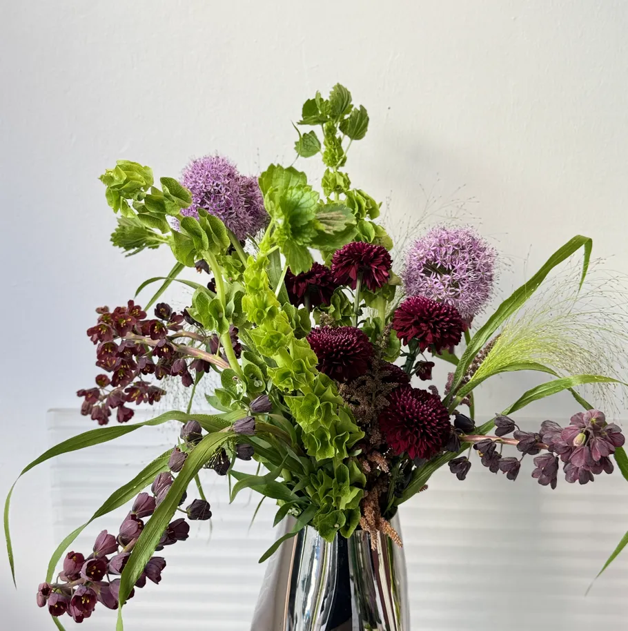Colorful flower arrangement in a reflective vase.