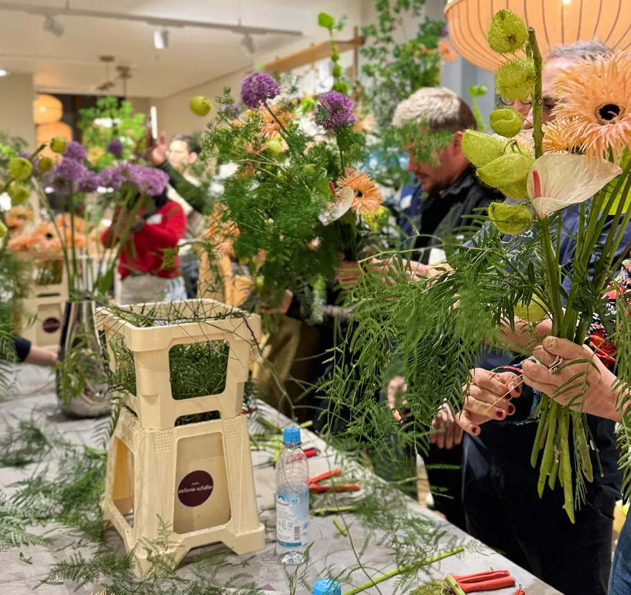 People arranging flowers in a workshop setting.