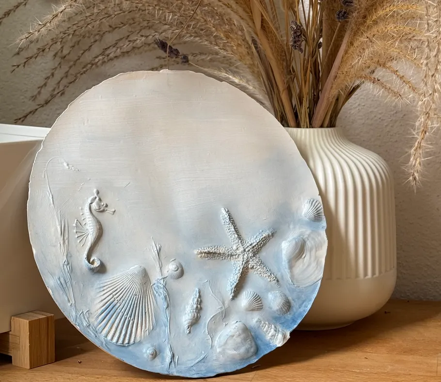 Clay disk with sea creature reliefs on table.