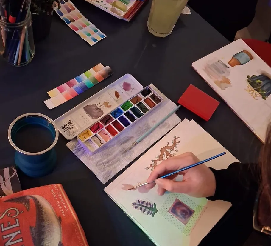 Person malt mit Aquarellfarben auf Papier.