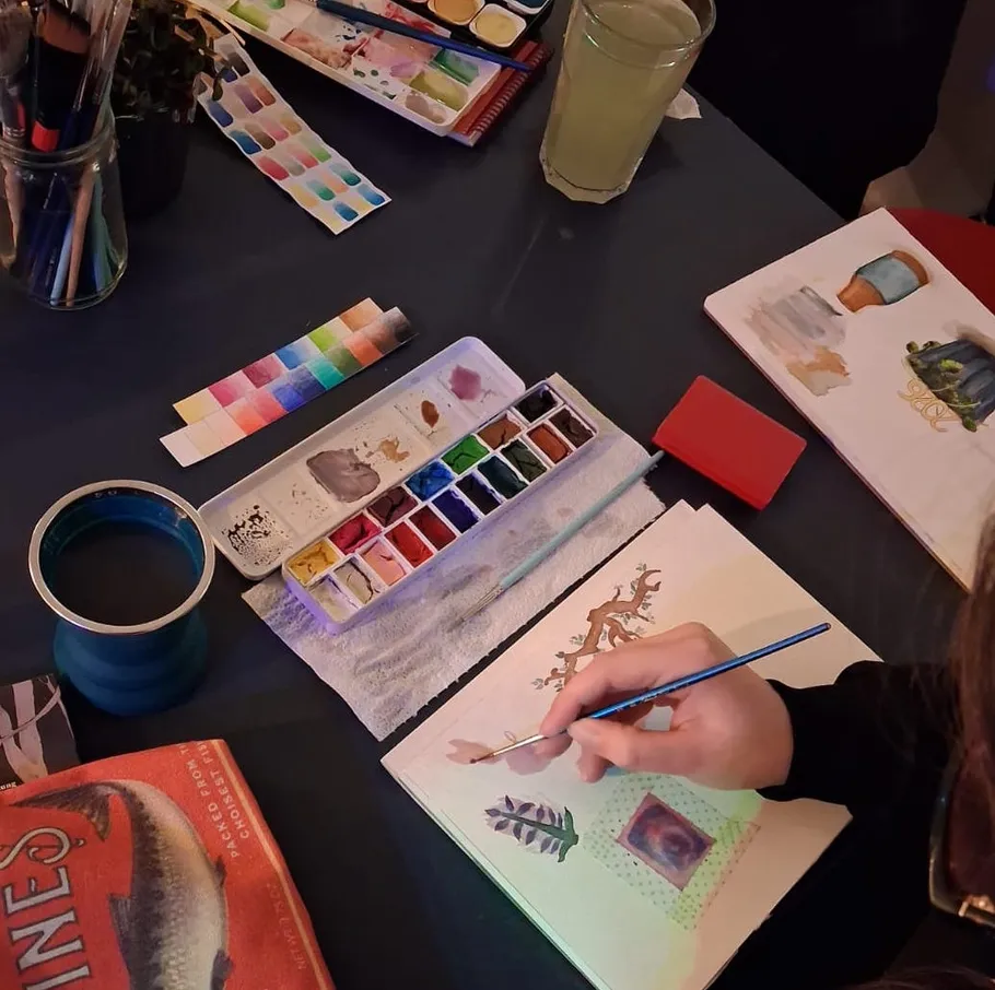 Person painting at a desk with watercolors.