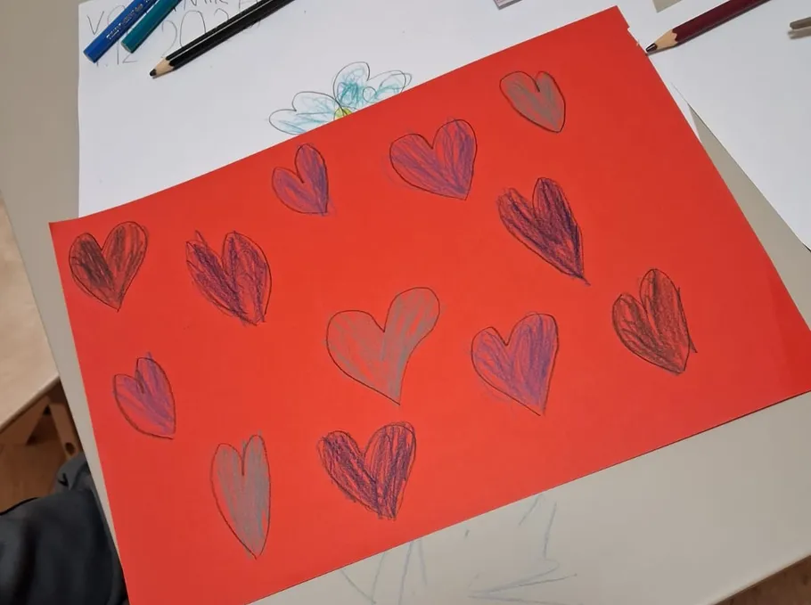 Paper with hand-drawn hearts on desk.