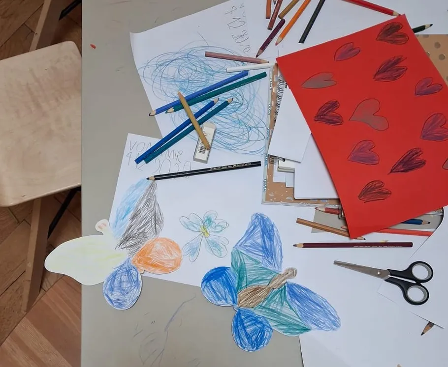 Tisch mit bunten Zeichnungen und Stiften.