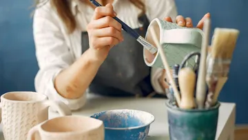 Person painting pottery in art studio.