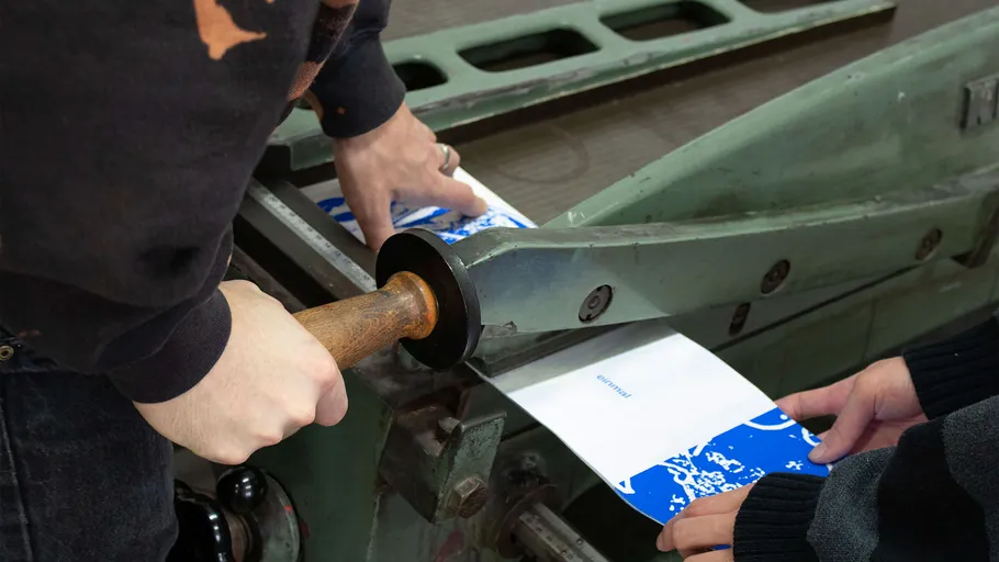 Hände bedienen einen manuellen Papierschneider.