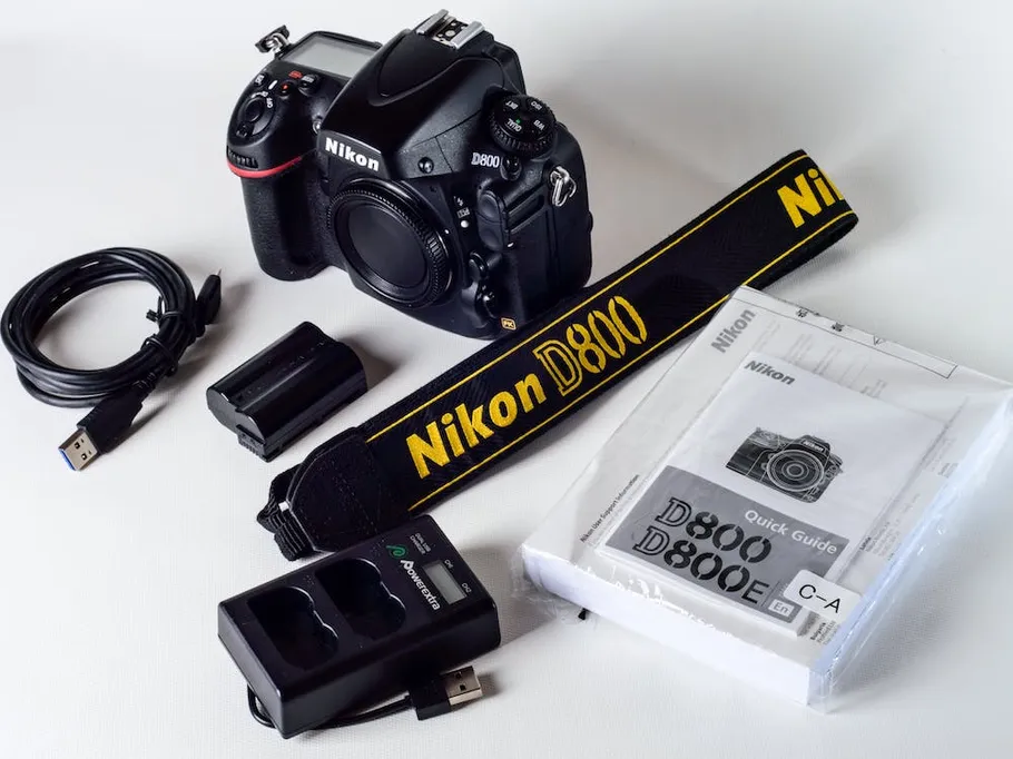 Kamera, Zubehör und Anleitung auf einem weißen Hintergrund.