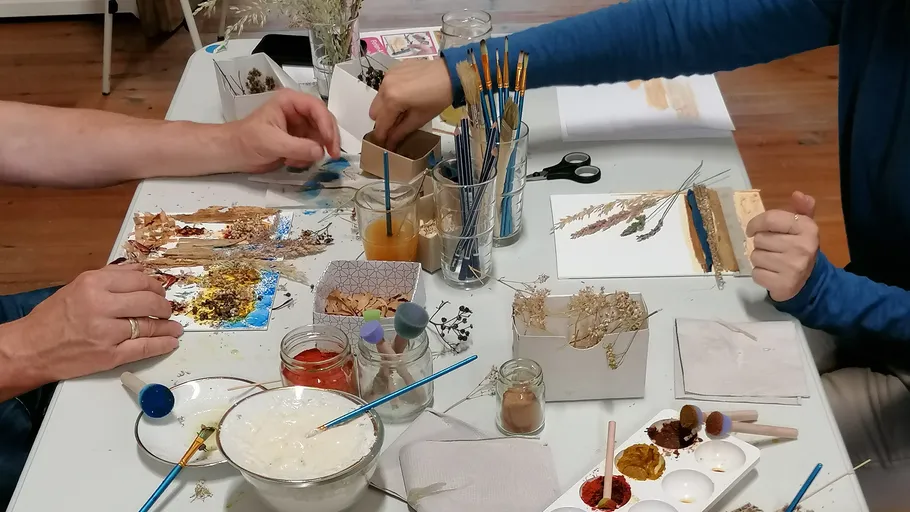 Zwei Personen basteln mit Naturmaterialien auf Tisch.