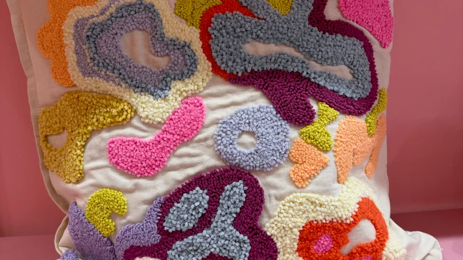 Buntes strukturiertes Kissen mit abstrakten Mustern.