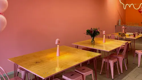 Rosa Café mit Tischen und Stühlen.