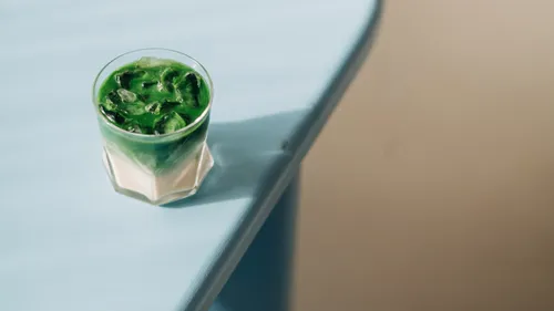 Eiskalter Matcha-Latte auf blauem Tisch.
