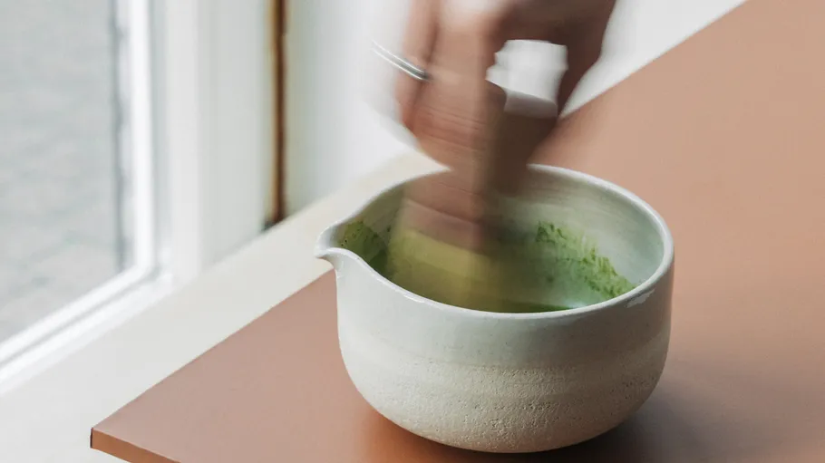 Person schlägt Matcha in einer Keramikschale.
