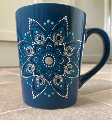 Blue mug with mandala design on tiled floor.