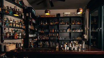 Dimly lit bar with shelves of liquor bottles.