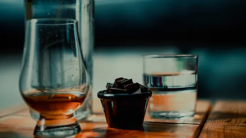 Whiskey, Schokolade, Wasser auf Holztisch.