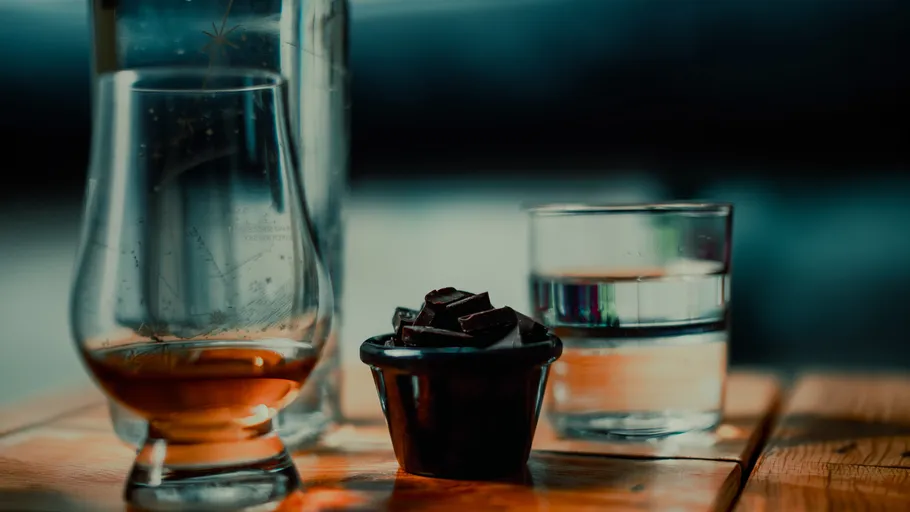 Whiskey, Schokolade, Wasser auf Holztisch.