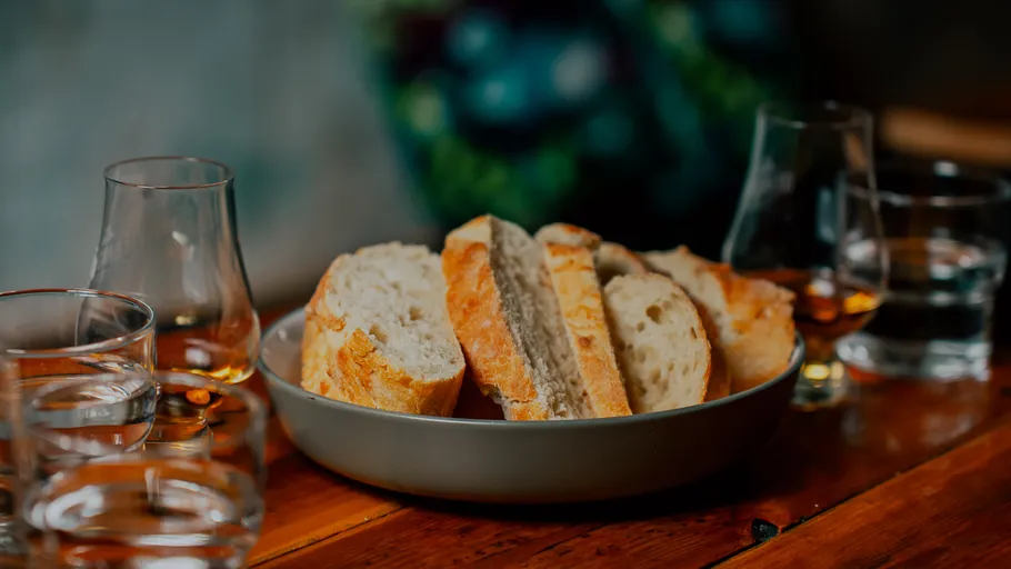 Bread slices on plate, surrounded by glasses.