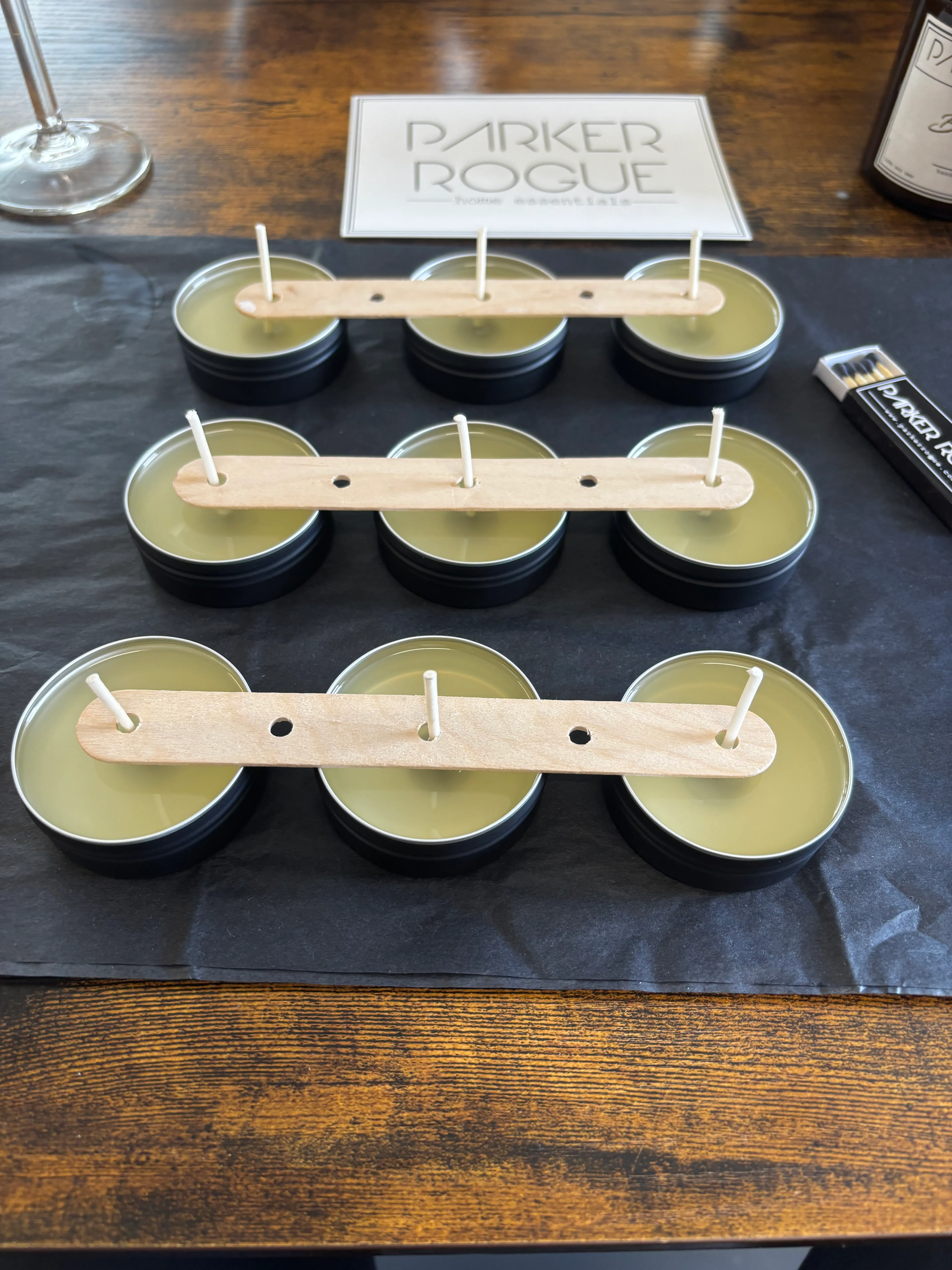 Candles with wicks in tins on a table.