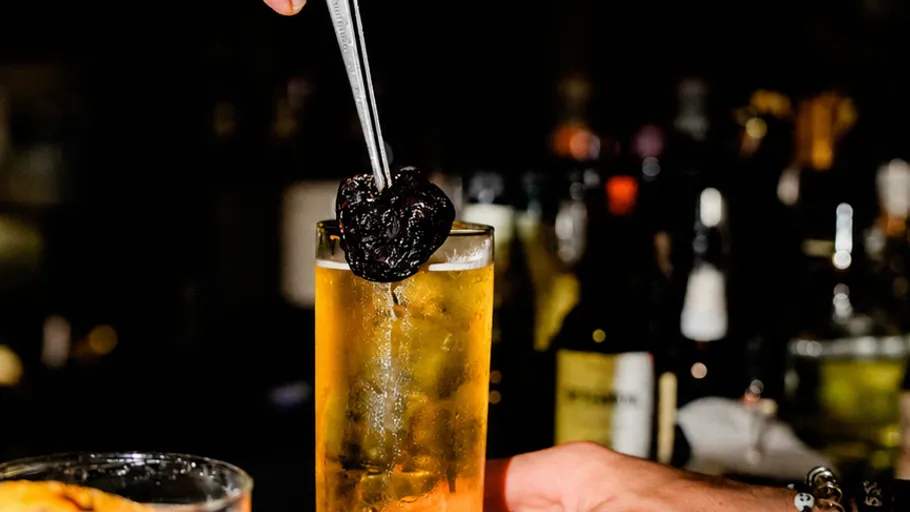 Barkeeper platziert Pflaume im Cocktailglas.