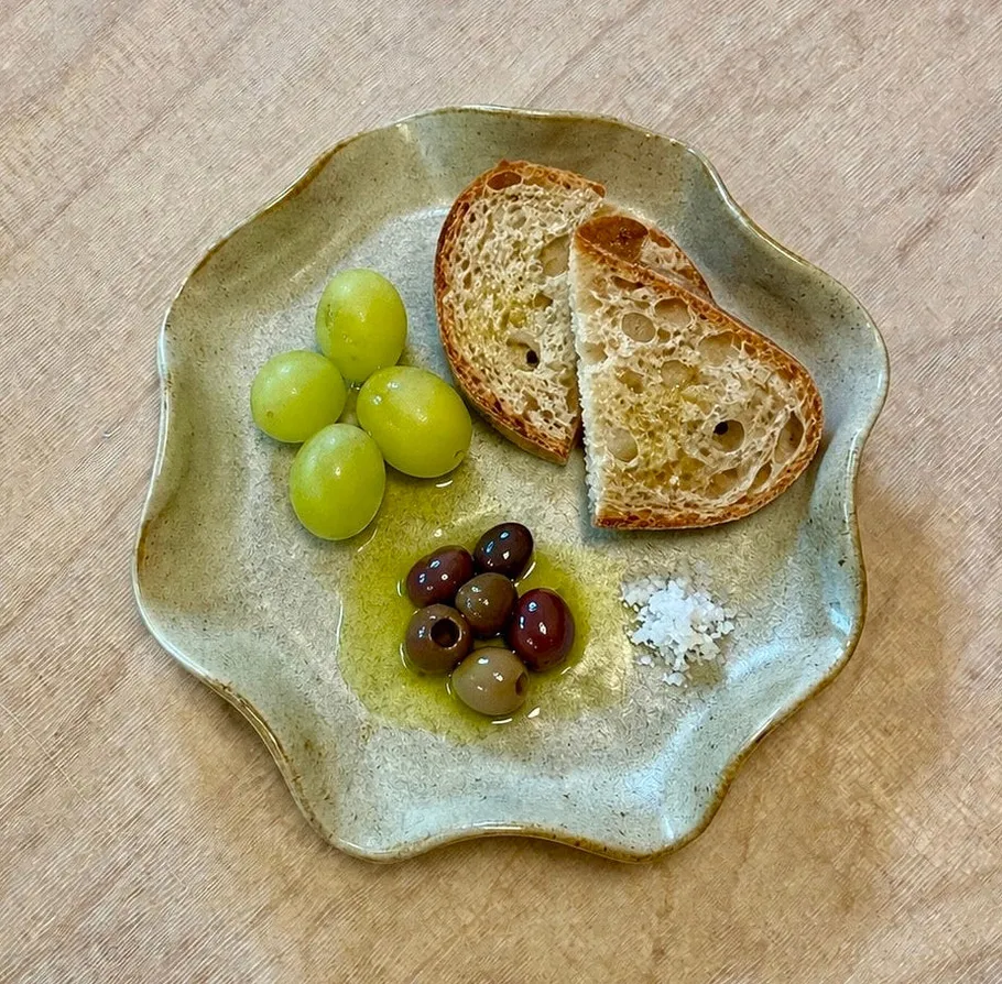 Teller mit Trauben, Brot, Oliven und Salz.