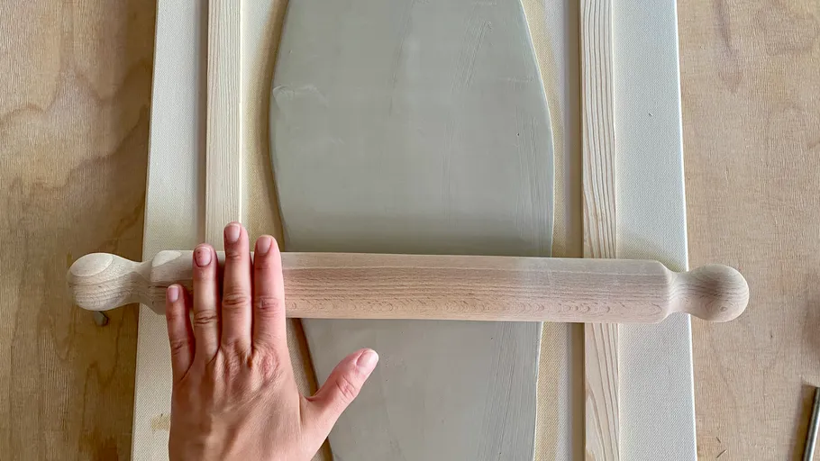 Hand holds rolling pin over dough frame.