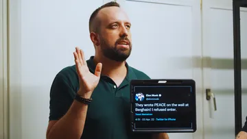 Man holding a tablet showing a tweet.