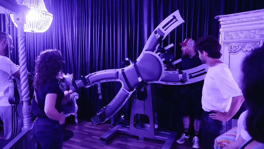 Personen betrachten großen mechanischen Stuhl im Raum.