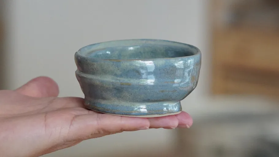 Keramikschale auf Hand; unscharfer Hintergrund.