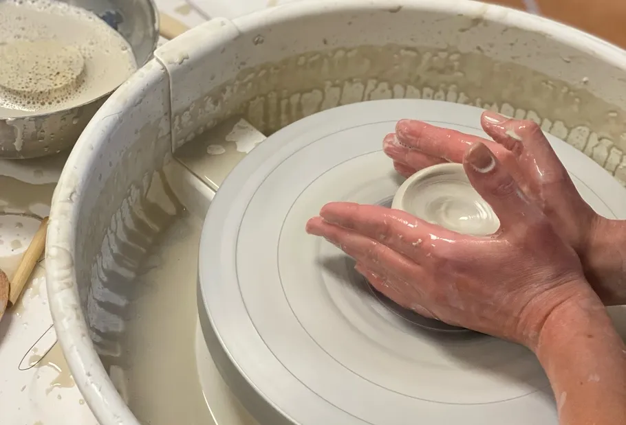 Hands shaping clay on a potter's wheel.