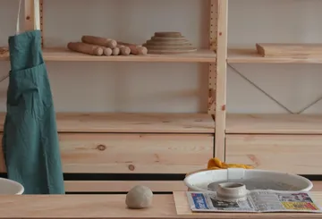Töpferwerkstatt mit Werkzeugen, Schürze, Ton und Scheibe.
