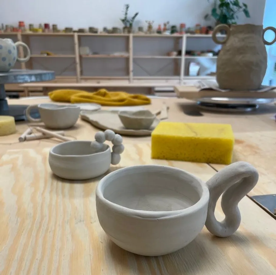 Clay cups and tools on pottery table.