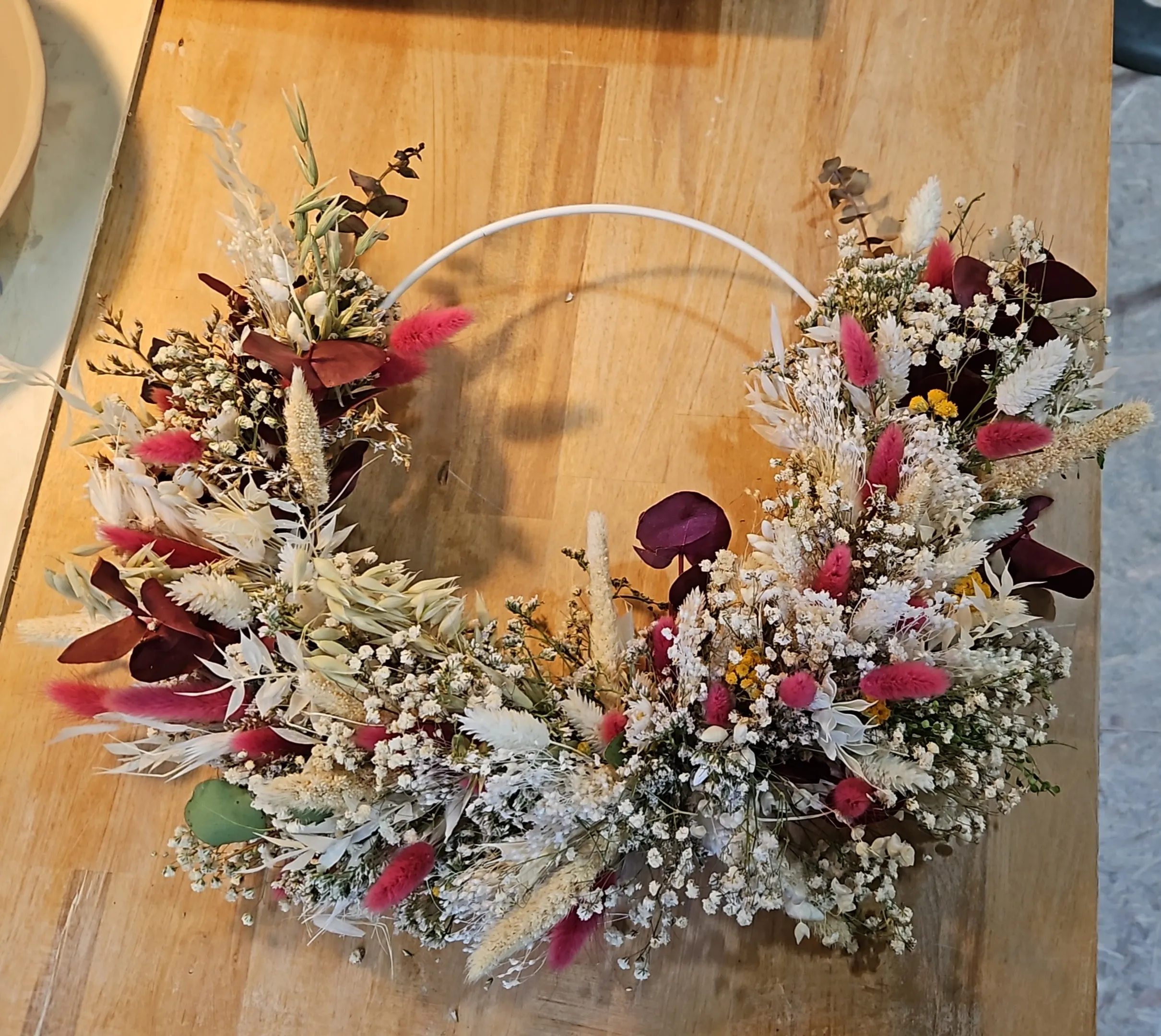Blumenkranz mit Trockenblumen auf Tisch.