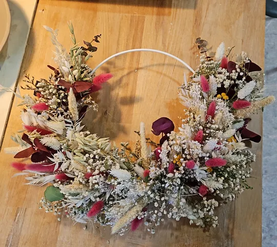 Blumenkranz mit Trockenblumen auf Tisch.