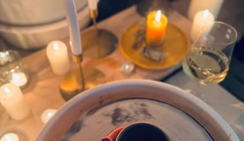 Candles and pottery on table with wine.