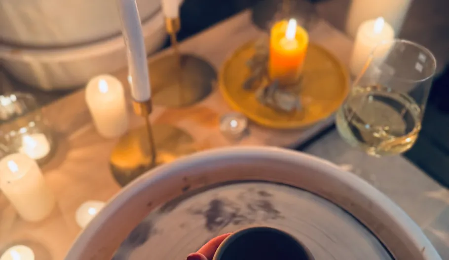 Candles and pottery on table with wine.