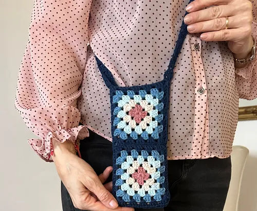 Häkelhandtasche von Frau in rosa Bluse gehalten.