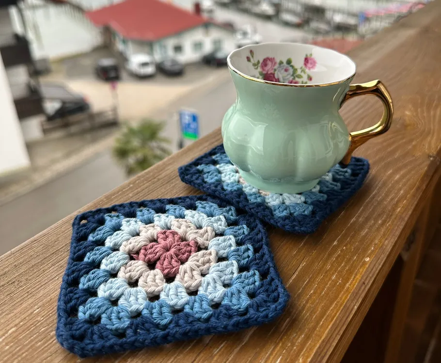 Teetasse auf gehäkelten Untersetzern, Balkon draußen.