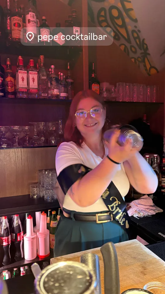 Person schüttelt Cocktailshaker hinter Bar.