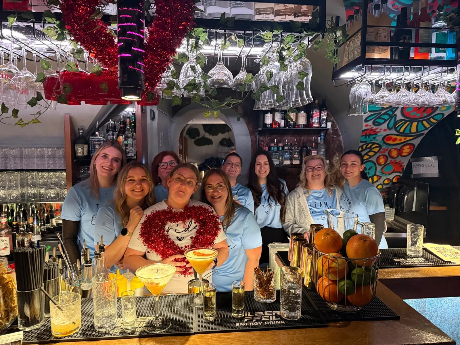 Gruppe von Frauen posiert hinter einer Bar.