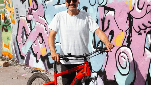 Mann steht mit Fahrrad in Graffiti-Gasse.