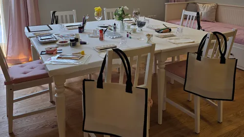 Tisch mit Bastelzubehör, Taschen und Stühlen gedeckt.