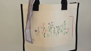 Beiger Stoffbeutel mit Blumenstickerei.