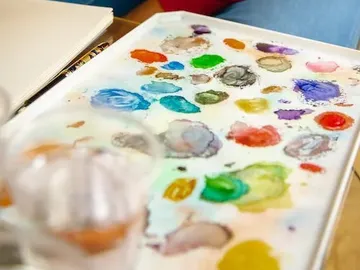 Palette with paints, plus glasses and sketchpad.